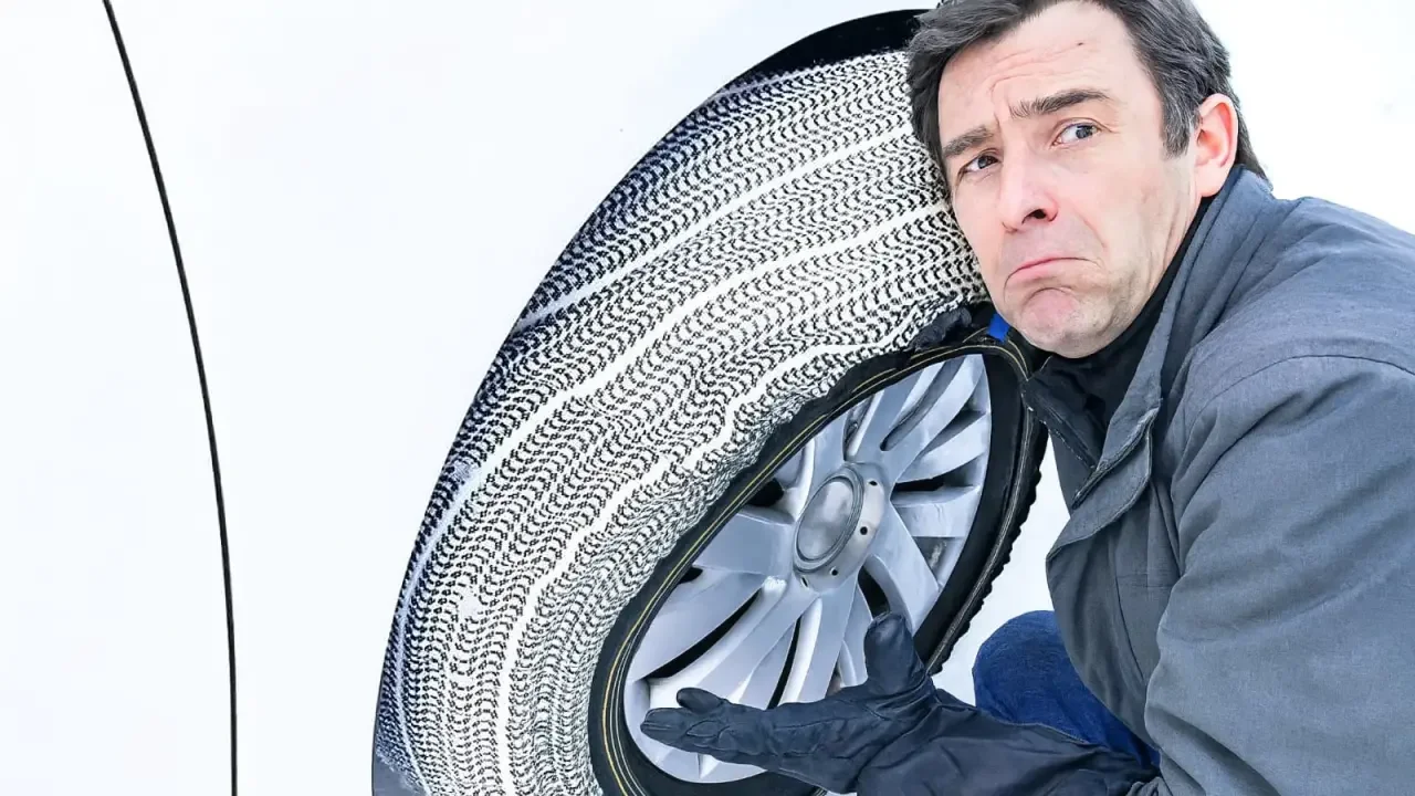 Chaîne textile enfilée sur un pneu de voiture dans la neige en montagne
