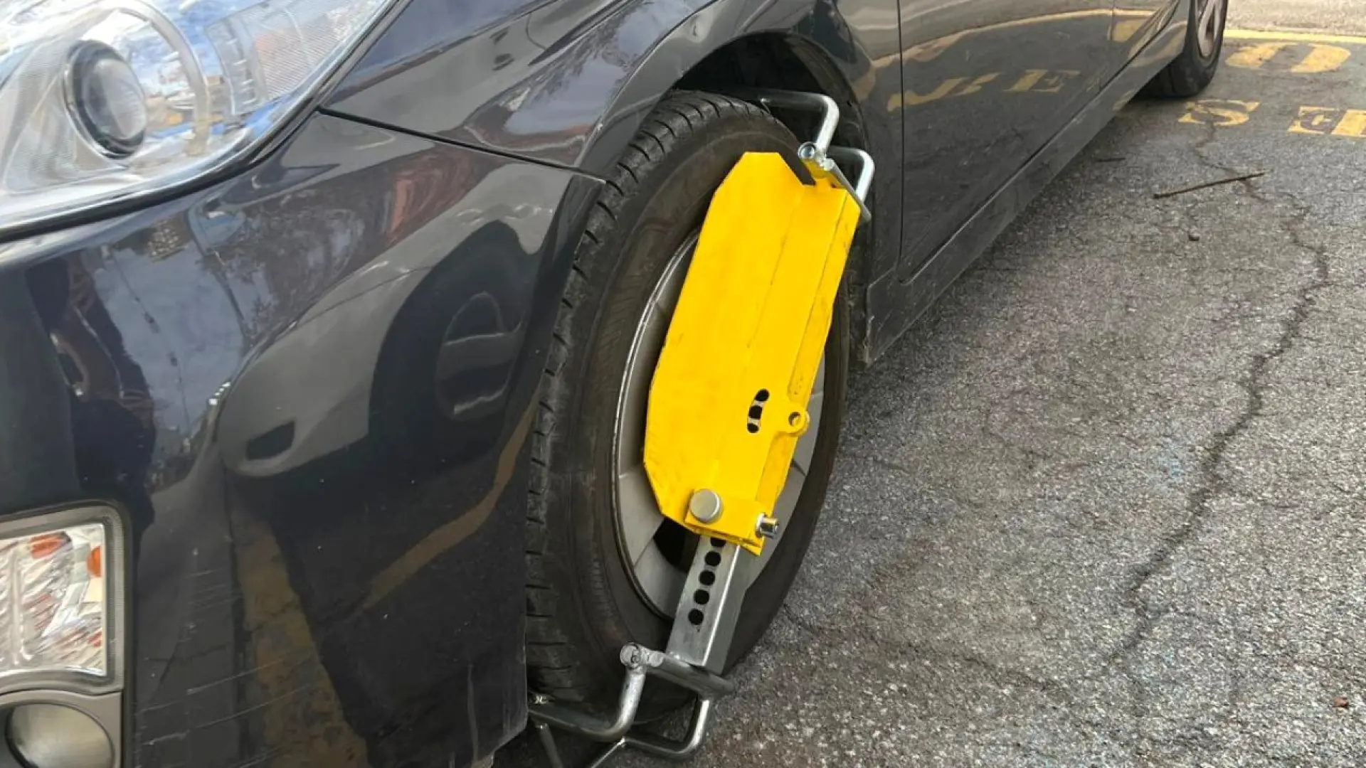 Sabot de Denver jaune verrouillé sur la roue d'une voiture immobilisée par la police pour alcoolémie