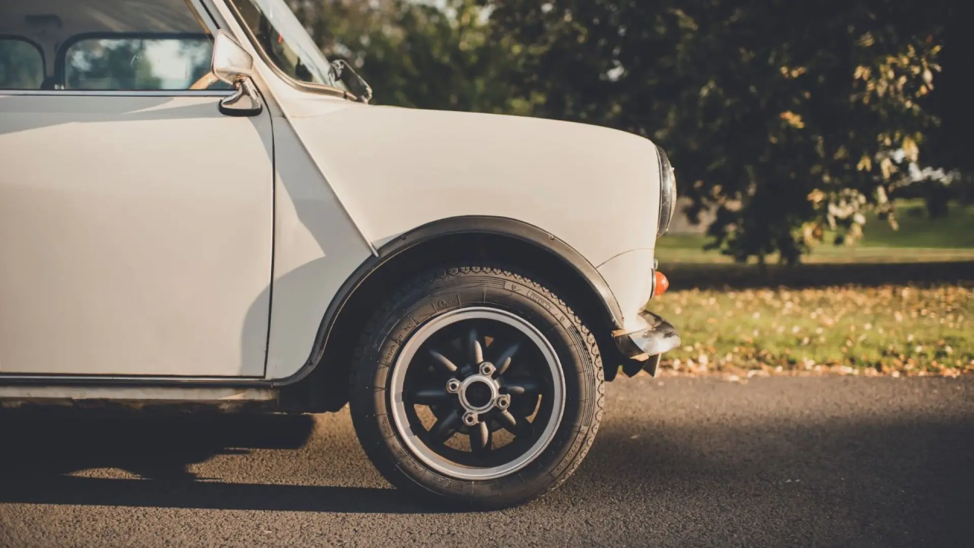 Mini Cooper classique des années 60 roulant sur route sinueuse, illustrant son héritage sportif légendaire