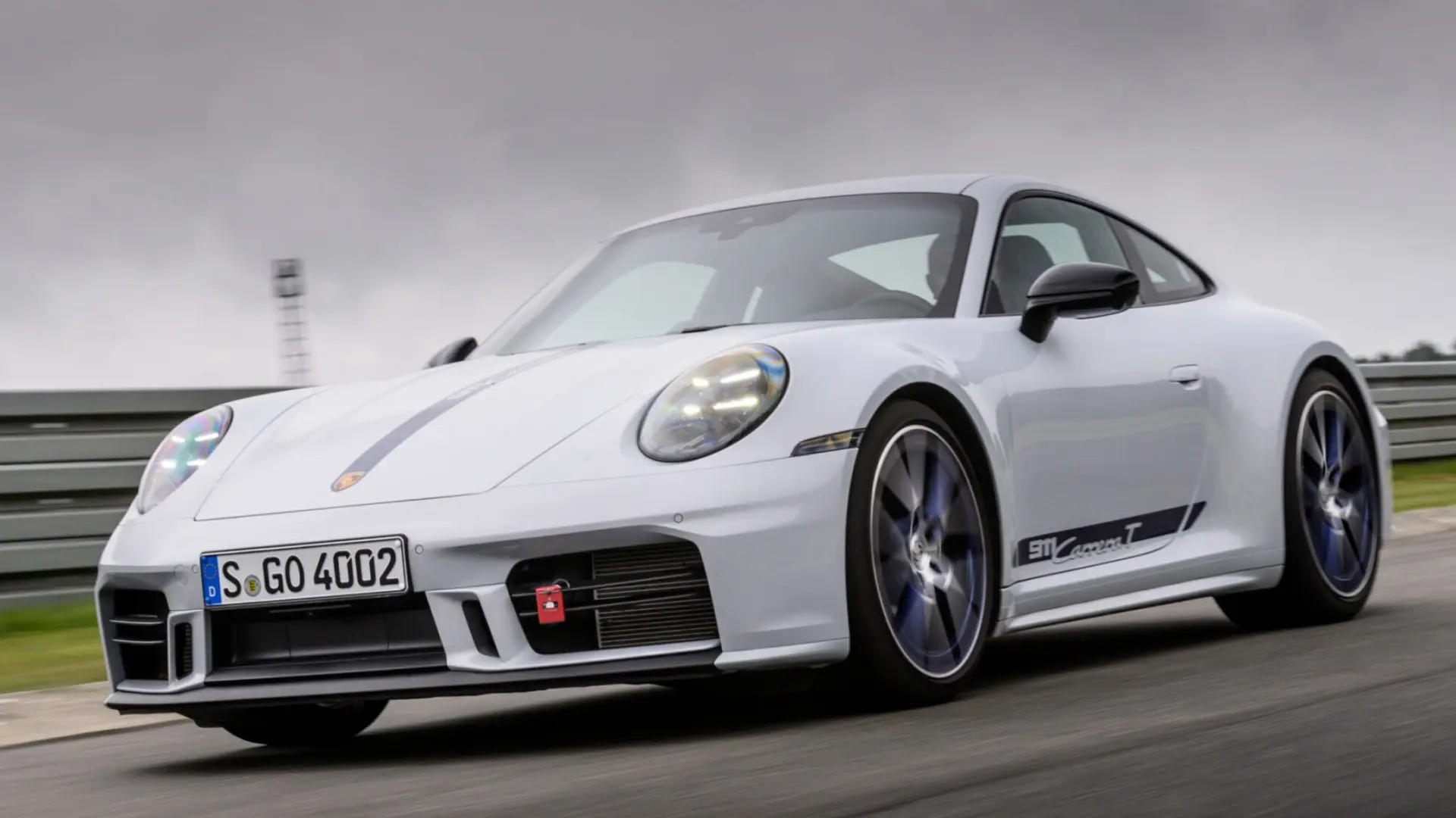 Porsche 911 Carrera T 992.2 blanche en action sur route, vue de trois-quarts avant avec boîte manuelle