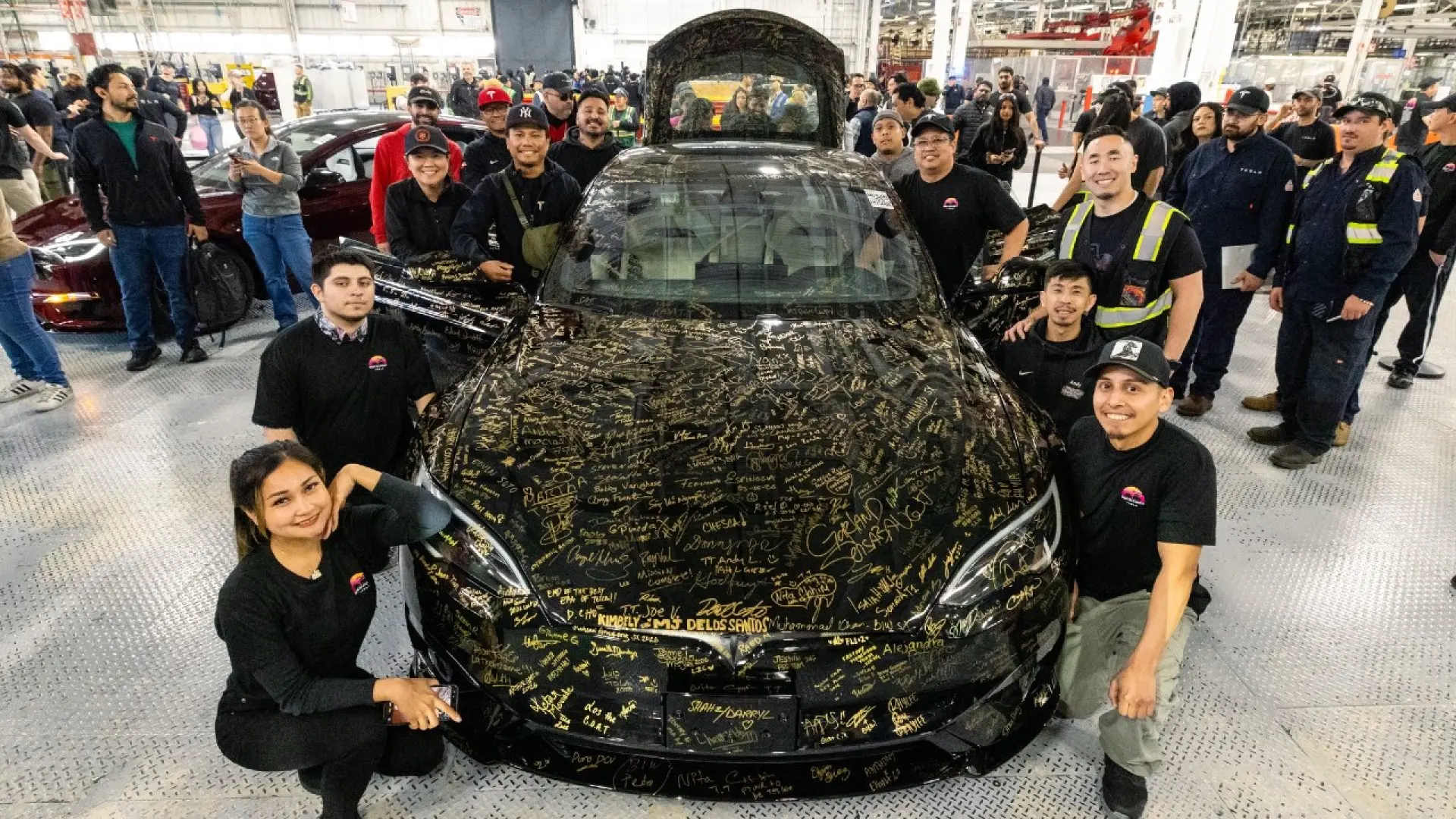 Dernier Model S noir produit par Tesla entouré des employés de l'usine de Fremont avec signatures sur la carrosserie