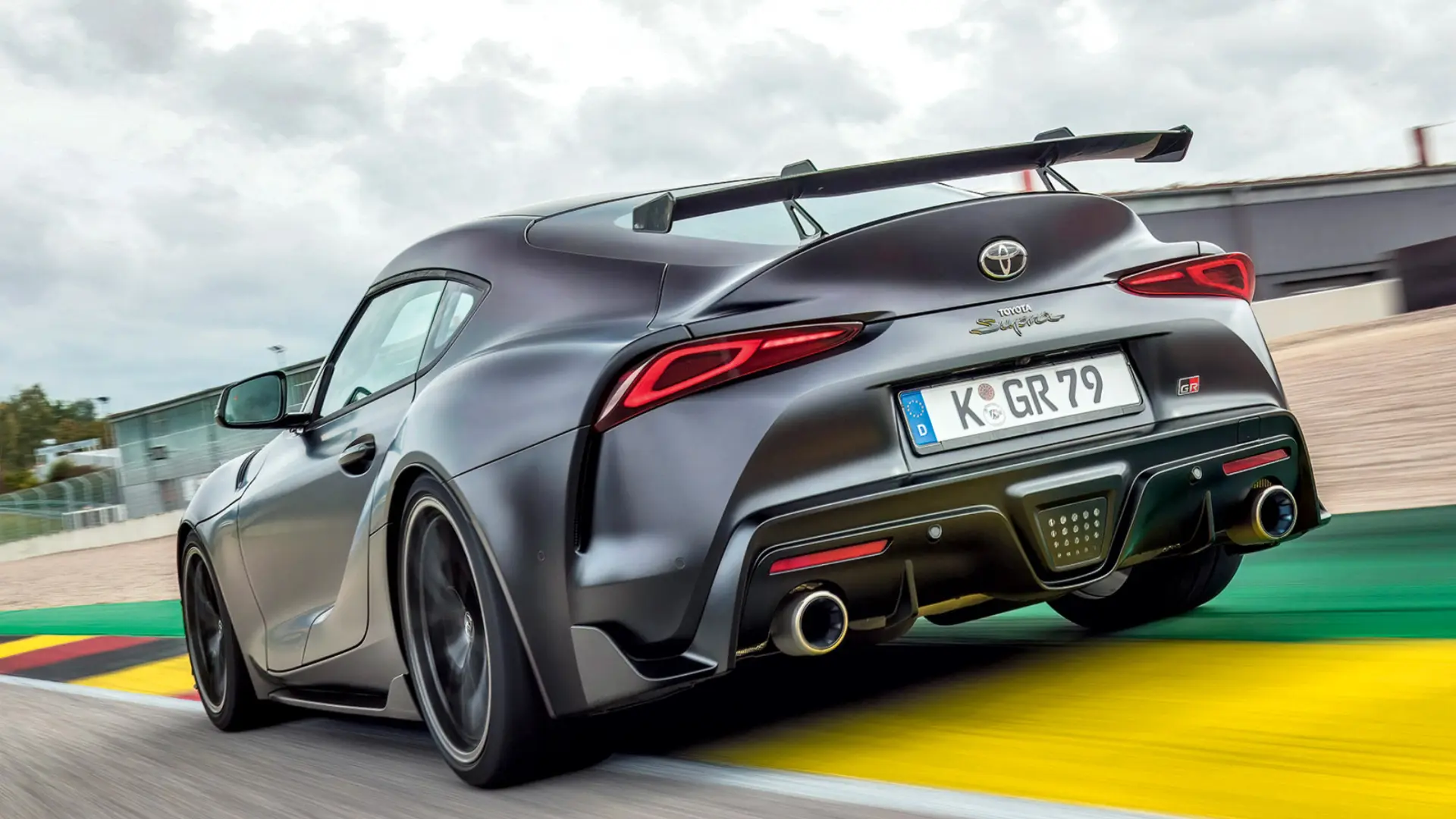 Toyota Supra Final Edition noire sur circuit, vue de trois-quarts avant avec aileron et échappement Akrapovic